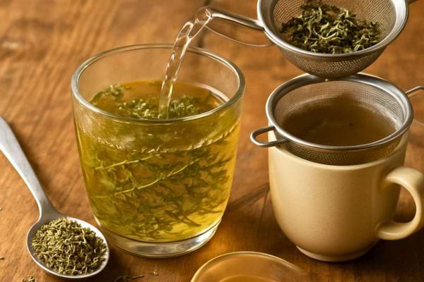 Une infusion de thym est en cours de préparation avec un filtre métallique.