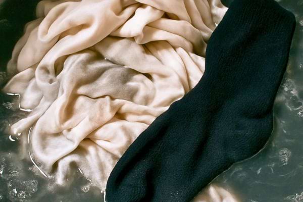 Un v&ecirc;tement clair et une chaussette fonc&eacute;e trempent ensemble, risque de d&eacute;coloration.