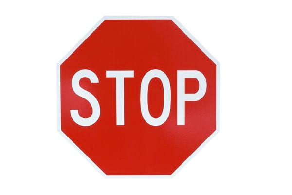 Panneau octogonal rouge avec le mot « stop » en lettres blanches sur fond clair.