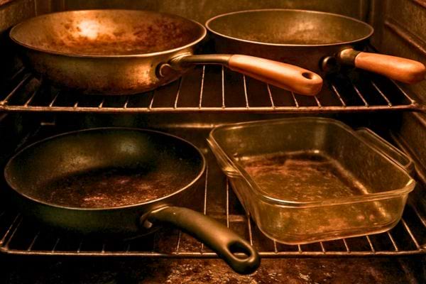 Plusieurs poêles et un plat en verre chauffent à l’intérieur d’un four.