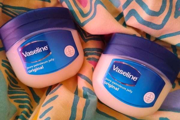 Deux pots de vaseline bleus posés sur un tissu coloré.