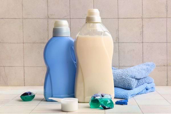 Bouteilles de lessive et serviettes bleues pos&eacute;es sur un plan carrel&eacute;.