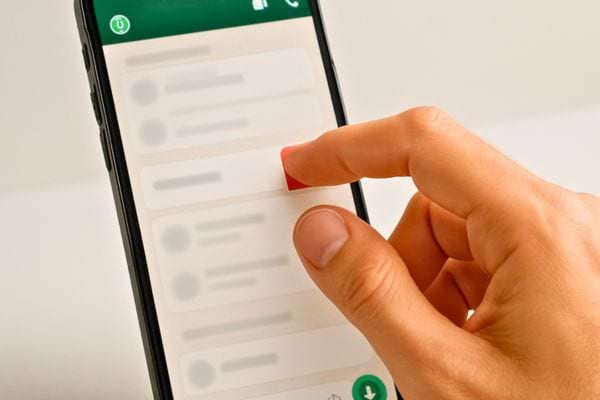 Un doigt glisse sur un message WhatsApp pour le supprimer.