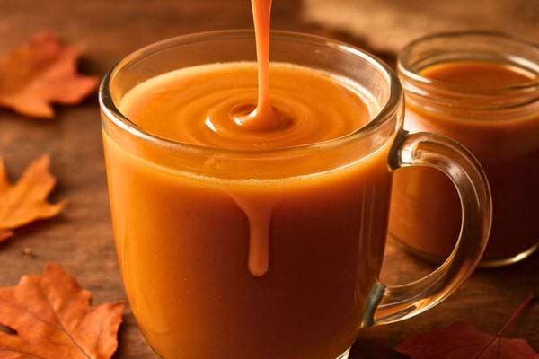 Caramel liquide verse dans une tasse en verre remplie dune boisson onctueuse aux tons chauds.