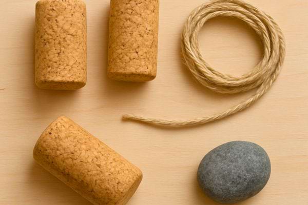Des bouchons en liege une corde et une pierre sont poses sur une surface en bois clair.