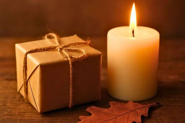 Un petit cadeau emballe et une bougie allumee decorent une scene chaleureuse aux tons d’automne.