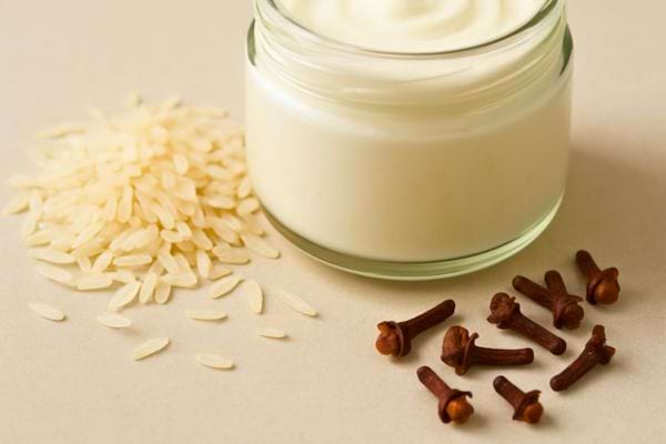 Pot de creme blanche accompagne de grains de riz crus et clous de girofle