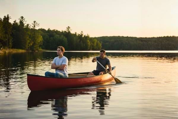 Un homme qui rame sur une barque et un autre ne faisant rien