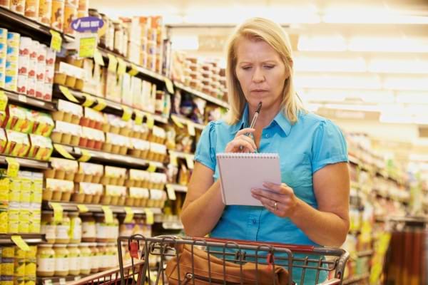 Une femme dans un supermarché avec une liste de courses papier