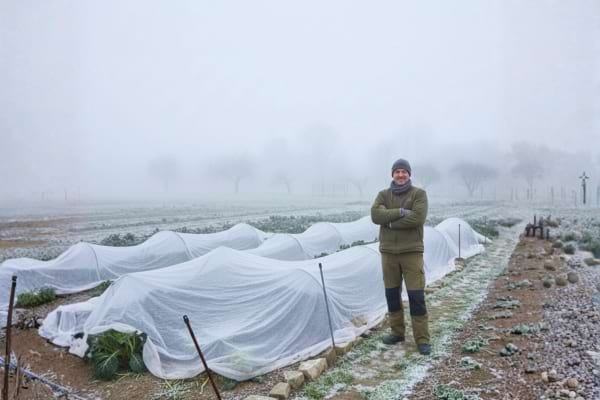 Photo réelle d’un jardinier souriant devant un potager bien protégé