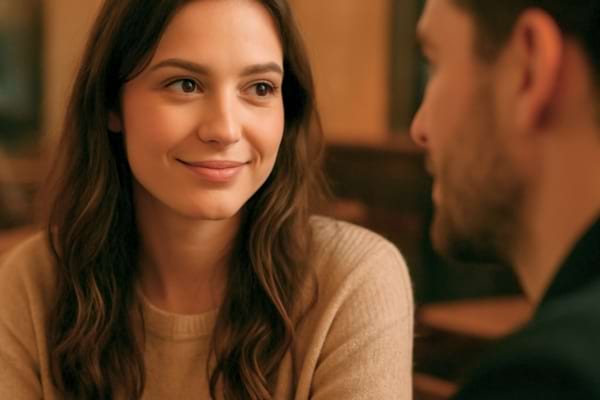 Gros plan sur une femme qui regarde un homme avec un sourire l&eacute;ger,