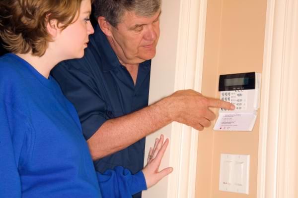 Un homme montre comment fonctionne un syst&egrave;me d'alarme de maison &agrave; une femme