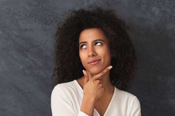 Une femme réfléchit en regardant vers le haut avec un air interrogatif.