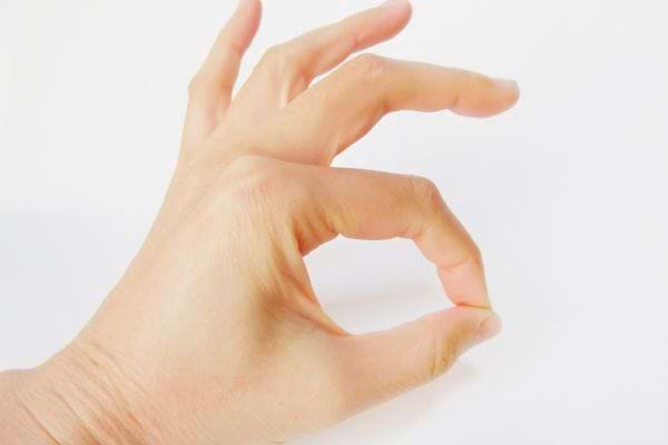Une main forme le geste ok avec les doigts contre un fond blanc lumineux.