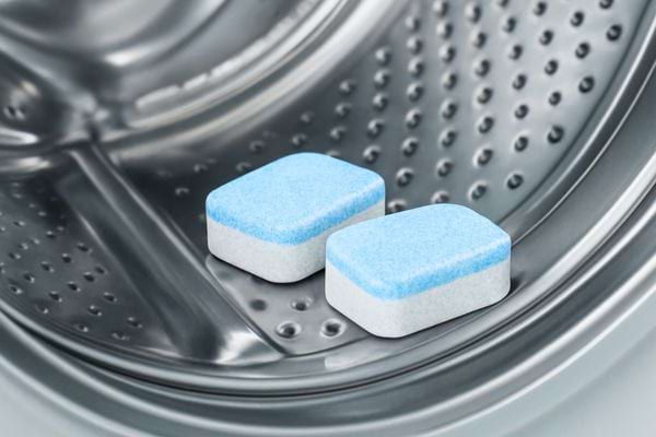 Deux pastilles de lessive posees a l interieur du tambour metallique de la machine a laver.