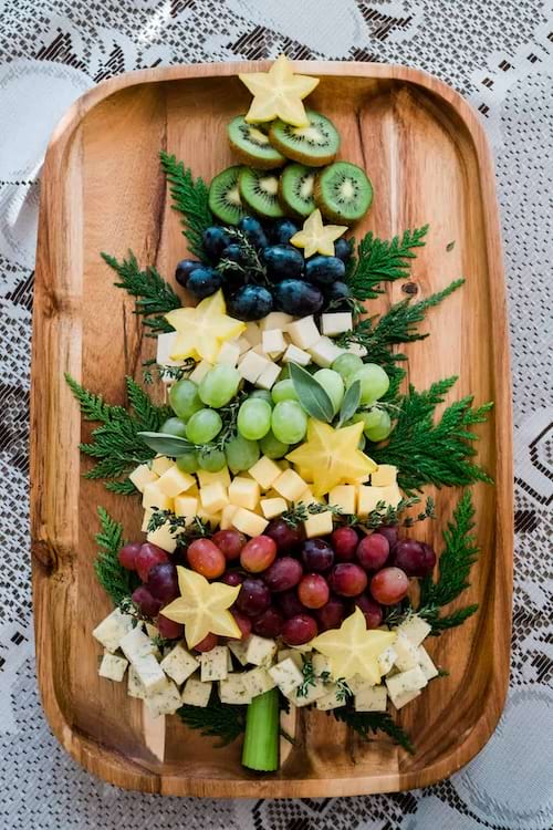 une planche ap&eacute;ro de No&euml;l en forme de sapin avec du fromage et des fruits exotiques