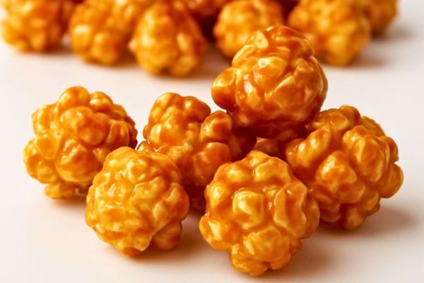 Gros plan sur des popcorns enrobes de caramel dores poses sur un fond clair.