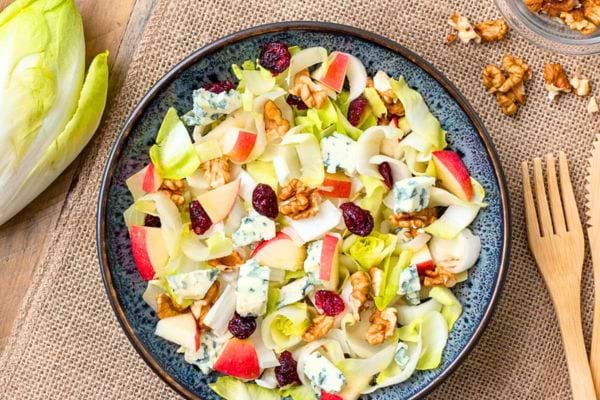 une salade de noël avec des endives, des noix, des cranberries, du fromage bleu