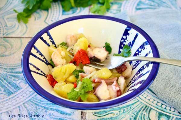 une salade avec du poulpe, des pommes de terre, des herbes fraîches