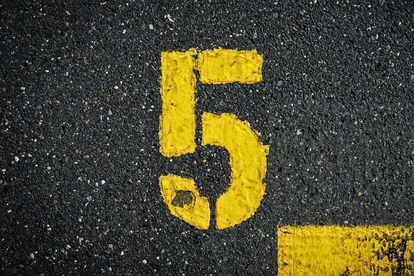 Le chiffre cinq est visible en peinture jaune usee. Il suggere un marquage ou une indication au sol.