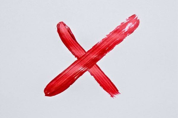 Une grande croix rouge est peinte sur fond clair. Elle symbolise refus interdiction ou negation nette.