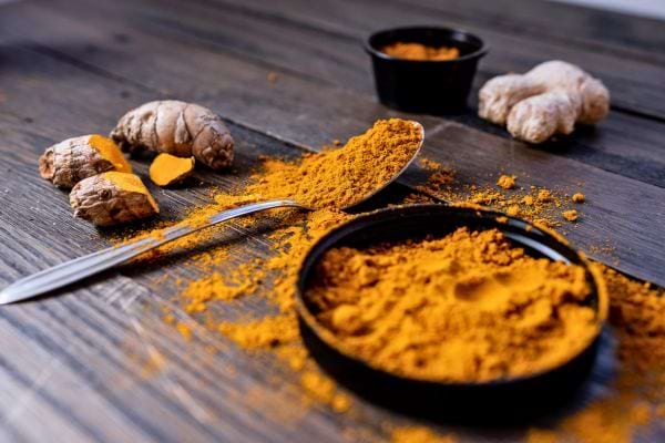 poudre de curcuma avec racines de gingembre posees sur une table en bois rustique