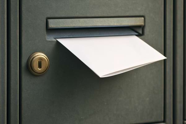 une bo&icirc;te aux lettres d&rsquo;immeuble, un coin de papier blanc l&eacute;g&egrave;rement visible &agrave; l&rsquo;int&eacute;rieur