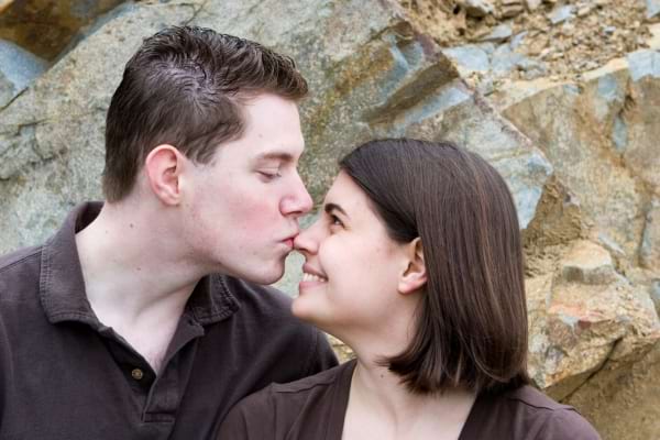 couple en promenade dans un parc, l&rsquo;homme embrasse le bout du nez de la femme