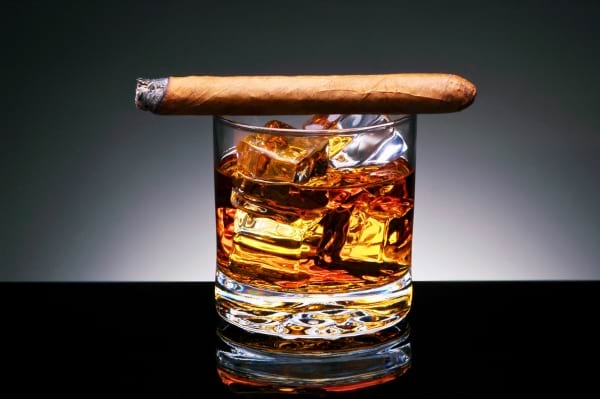 Un cigarre posé sur un verre d'alcool