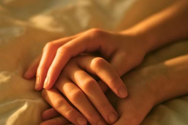 ros plan sur deux mains qui s'effleurent ou s'entrelacent sur un drap blanc