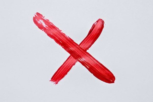 Croix rouge peinte sur fond blanc symbolisant une interdiction claire ou une pratique a eviter absolument.