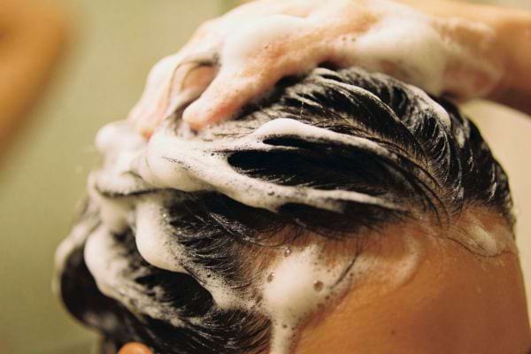cheveux mouilles masses avec shampoing moussant sous la douche