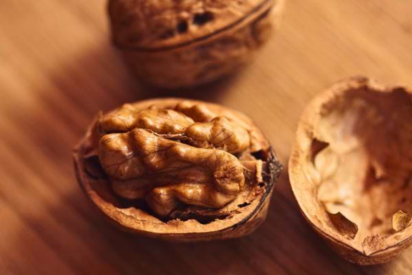 noix entieres et coque ouverte posees sur une surface en bois