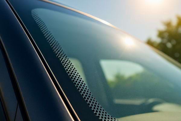 vue exterieure du pare brise montrant la bande pointillee noire pres du montant