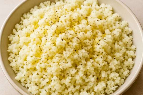Un bol de puree de chou fleur est assaisonne d huile et de poivre. La texture est fine et aerienne.