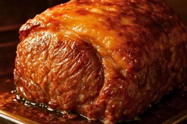 gros plan sur un roti dore avec jus de cuisson brillant et appetissant