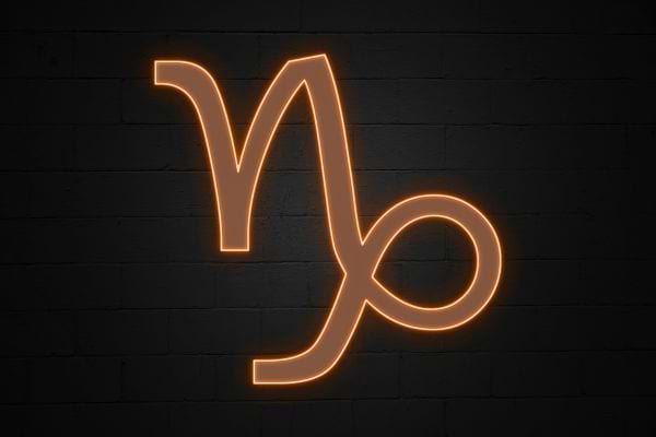 Le symbole du capricorne est affiche en neon orange. Il symbolise rigueur ambition et perseverance.
