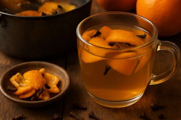 tasse de boisson chaude avec morceaux d orange et clous de girofle sur fond rustique