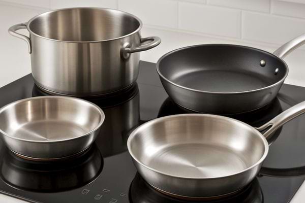 casseroles et poeles en inox posees sur une plaque a induction noire dans une cuisine moderne