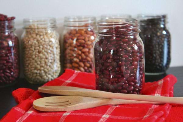 des bocaux en verre remplis de haricots et lentilles sont alignes sur une table