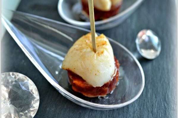 bouch&eacute;e de noix de saint Jacques avec du chorizo sur une cuill&egrave;re avec un pic