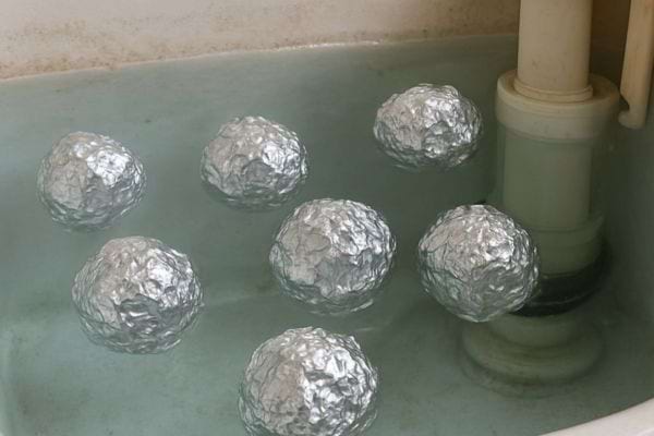 Boules de papier aluminium flottant dans eau verte d un reservoir wc.