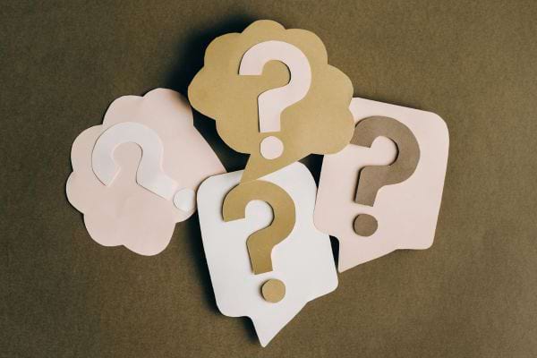 plusieurs bulles en papier avec des points dinterrogation poses sur un fond neutre