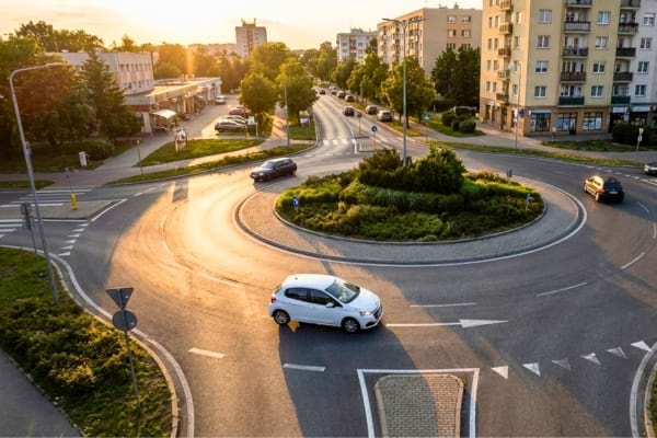 un rond-point avec une voiture blanche sur la file extérieure