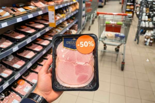 a Lidl supermarket aisle, close up on a hand holding a product with a bright orange discount sticker saying "-50%"