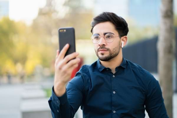 Un homme devant son t&eacute;l&eacute;phone en faceID