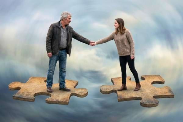 a couple holding hands but standing on two different floating puzzle pieces that are slightly drifting apart
