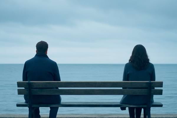 d'un couple vu de dos, assis sur un banc face à la mer, mais laissant un grand espace vide entre eux.