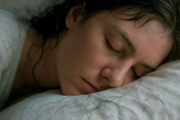 jeune femme endormie sur un oreiller avec les cheveux encore humides