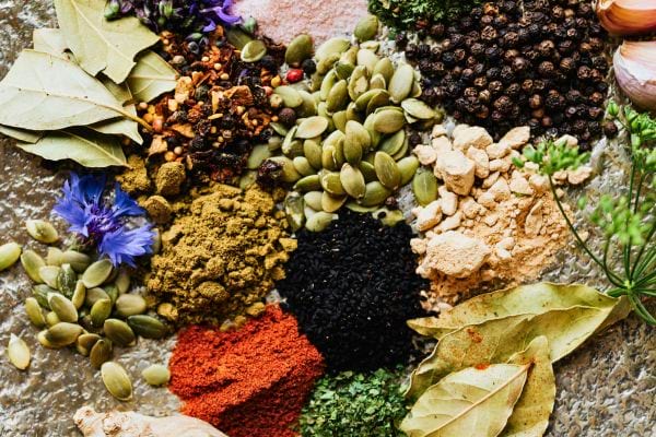 assortiment depices graines feuilles sechees et poudres disposees en cercle sur une surface rustique